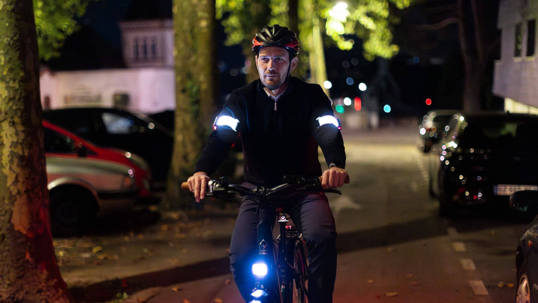 Cycliste roulant de nuit avec casque et equipement brassards lumineux sur les bras